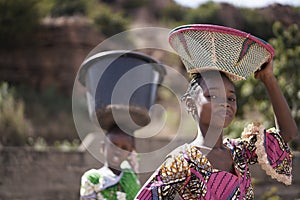 Two Proud African Girls Carrying Heavy Household Items On Their Head