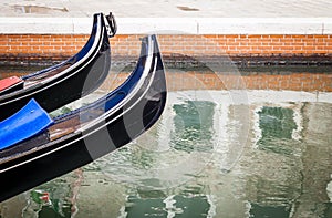 Two Prows Of Venetian Gondolas Above Canal Waters photo