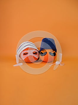 Two pumpkin with eye patches, facial mask and towel on orange background
