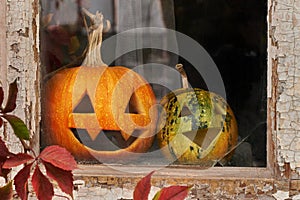 Two pumpkins for Halloween laughing on the windowsill of an old building.