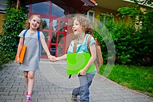 Two pupils of elementary school, boy and girl, on a schoolyard.