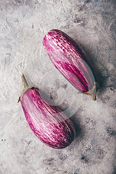 Two purple aubergines on light background