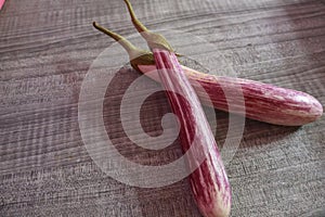 two purple eggplants with long white stripes on the table