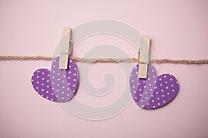 two purple hearts on clothespins on pink background - Valentine`s day concept