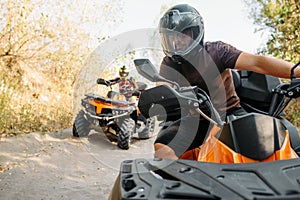 Two quad bike riders travels in forest, front view