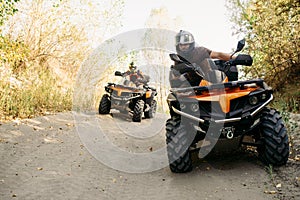 Two quad bike riders travels in forest, front view