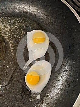 Two quail eggs are being fried on a pan