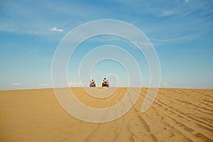 Two racers riding on atv in desert, afar view
