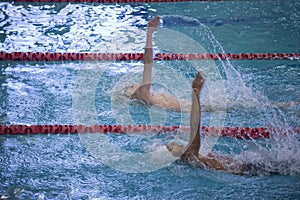 Two racially diverse swimmers competing doing backstroke