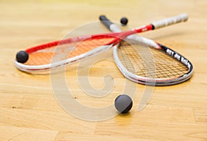 Two rackets and squash balls lie on the parquet floor