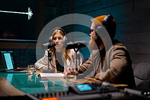 Two radio presenters in studio. Young man and woman while recording an audio podcast in a studio.