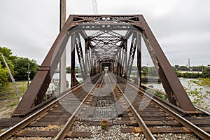 Two railroad train tracks lead into a rusty metal trestle bridge crossing the Schuylkill River in Philadelphia, Pennsylvania, USA