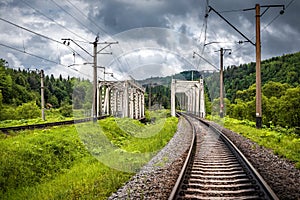 Two railway bridges in summer mountains under stormy sky