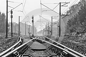Two railway tracks with electric power poles near a small train station
