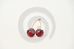 Two  raw cherries on a white background with an empty copy space for text, selective focus and toned image