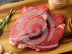 Two Raw Entrecote with garlic and rosemary, on a wooden board. close-up