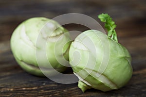 Two raw kohlrabies on a rustic wooden table.