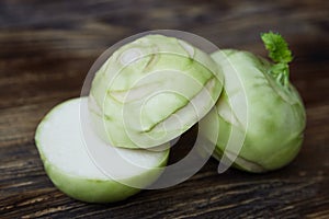 Two raw kohlrabies on the rustic wooden table, one is cut