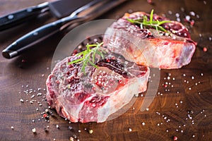 Two raw pieces beef shank on wooden butcher board with fork and