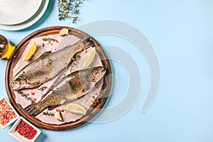 Two raw rainbow trouts on paper with thyme and lemon. Fish trout. Top view. Free space for your text