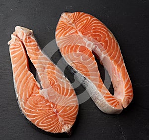 Two raw salmon steaks on a black background