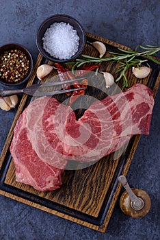 Two raw striploin steaks, garlic, pepper and rosemary