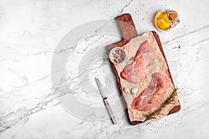 Two raw veal escalope on the old wooden cutting board, ready to cook, top view