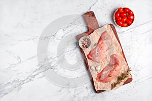 Two raw veal escalope on the old wooden cutting board, ready to cook, top view