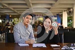 Two real estate agents sitting in office and smiling to camera.