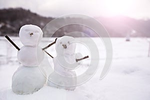 Two real tiny, little snowman in nature in snowy, cold day in mountains