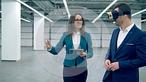 Two realtors use VR glasses while walking in a room.