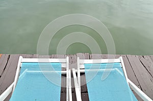 Two Recline chairs on dock facing a green lake.