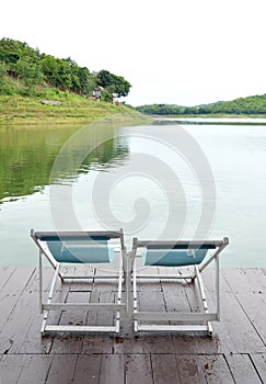 Two Recline chairs on dock facing a green lake.