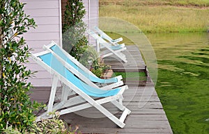 Two Recline chairs on dock facing a green lake. photo