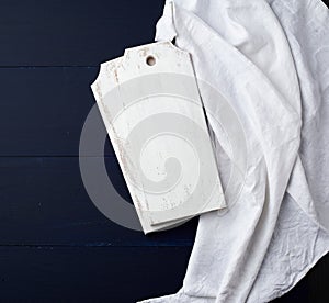 Two rectangular white cutting kitchen boards on a blue wooden background, next to a white textile towel, top view