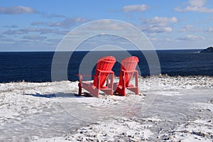 Two red Adirondack chairs on the Winter coast