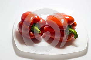 Two red bell peppers lie on a white plate