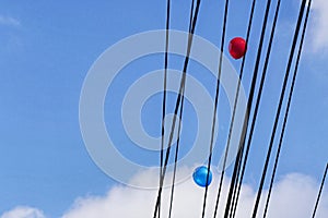 Two red and blue balloons are trapped in the cable