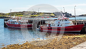 Two red boats moored in the harbor on Inishbofin Island