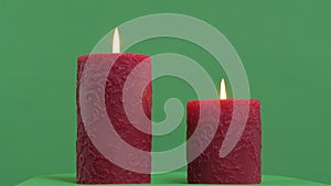 Two red candles burning on a green screen