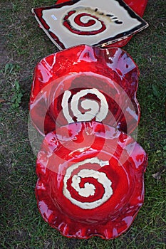 Two red ceramic plates with a white spiral drawn resting on the grass and very typical of Galicia, Spain