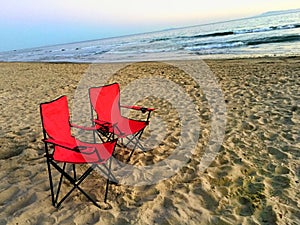 Two Red Chairs On The Beach Overlooking The Ocean