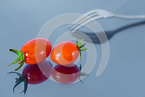 Two Red Cherry Tomatoes and One Fork on Mirror