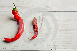 Two red chili peppers, on wooden background