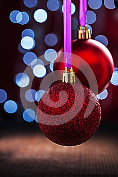 Two red christmas balls hanging on pink tape on old wooden table