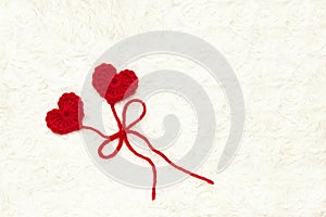 Two red crochet wool hearts and ribbon on white crochet background. The concept for 14 February, romantic Valentine day, love