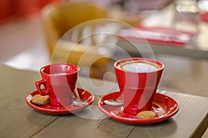 Two red cups of coffee with a biscuit. photo