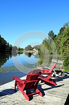 Two Red Deck Chairs Overlooking Reflection on Water