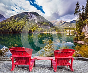 Two red deck chairs on the shore of the lake