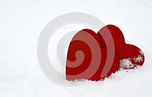 Two red decorative hearts on natural white snow background.Valentine`s Day greeting card.